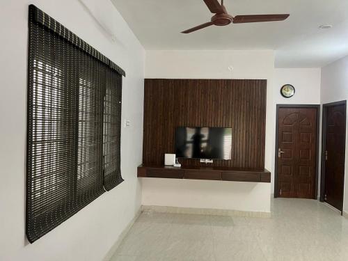 Cette chambre dispose d'une télévision et d'un mur avec une fenêtre. dans l'établissement Raj Nivas, à Mayiladuthurai