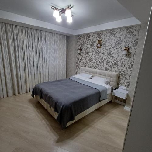 - une chambre avec un lit et un mur recouvert de papier peint dans l'établissement Apartament Buiucani Alba Iulia, à Chişinău