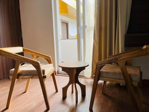 una stanza con due sedie, un tavolo e una finestra di Simran Aura Resort a Dehradun
