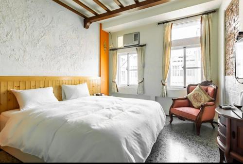 a bedroom with a large white bed and a chair at Chihkan Mansion in Tainan