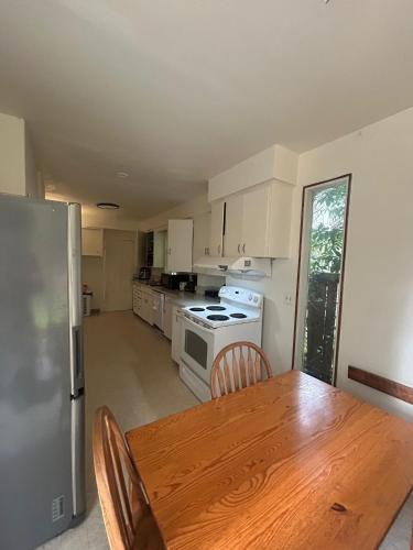 a kitchen with a wooden table and a refrigerator at Vancouver Guest House - Airport 10 Min - Free Parking & Fast Wi-Fi in Vancouver