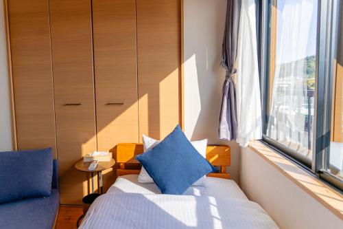 a bedroom with a bed with blue pillows and a window at Good Stay Apartment Nichinan - Sea View & Free Parking in Nichinan