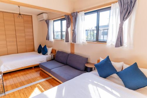 a room with a bed and a couch and windows at Good Stay Apartment in Nichinan
