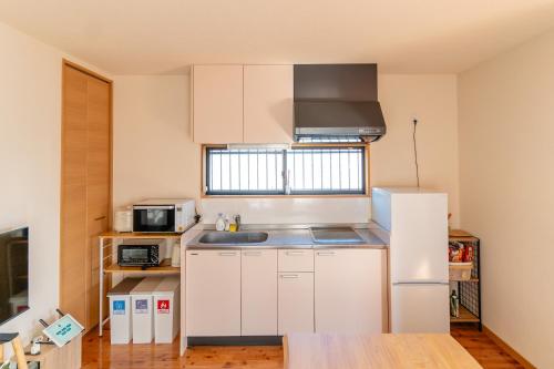 a small kitchen with white cabinets and a refrigerator at オーシャンフロント日南 絶景海ビュー 駐車場2台無料 Good Stay Apartment in Nichinan