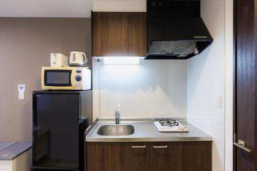 a small kitchen with a sink and a microwave at Niseko Hirafu Ski Resort Condo in Kutchan