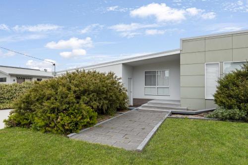 a large white house with a grass yard at Eleebana in Lake Tyers