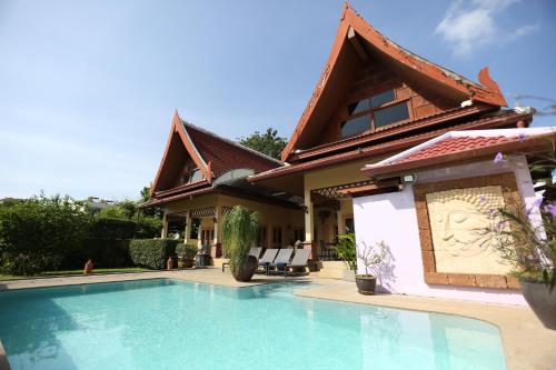 a house with a swimming pool in front of it at Beautiful 5BR Villa Felicity, Pool & Garden, near Naiharn in Rawai Beach