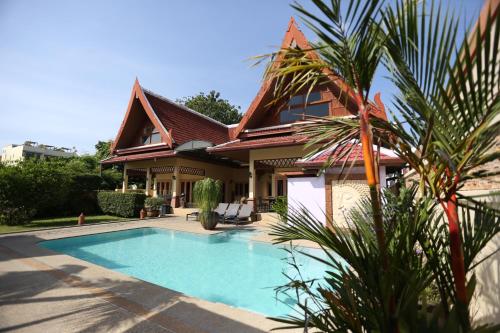 a house with a swimming pool in front of it at Beautiful 5BR Villa Felicity, Pool & Garden, near Naiharn in Rawai Beach