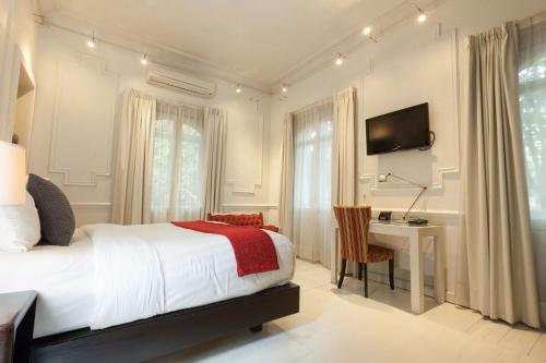 a bedroom with a bed and a desk and a television at Hotel Villa Condesa in Mexico City