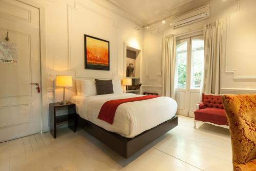 a bedroom with a large bed and a red chair at Hotel Villa Condesa in Mexico City