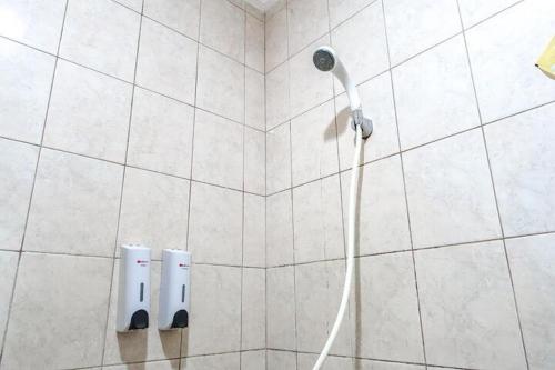 una ducha con una manguera pegada a una pared de azulejos en RedDoorz Plus near Brawijaya Museum, en Malang