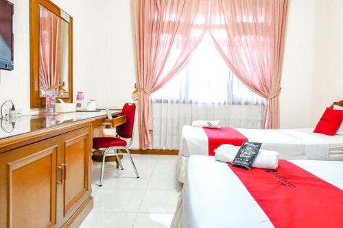 Habitación de hotel con 2 camas, escritorio y lavamanos en RedDoorz Plus near Brawijaya Museum, en Malang