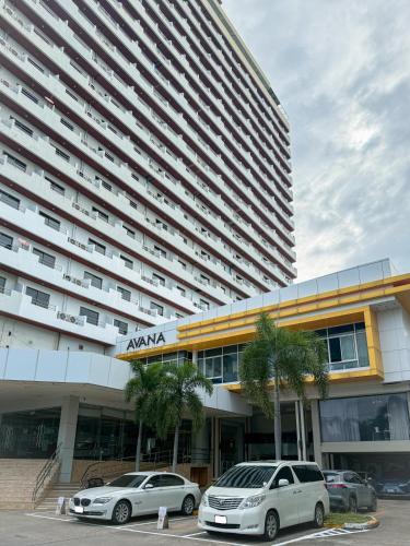 two cars parked in front of a large building at Avana Residence in Bangna