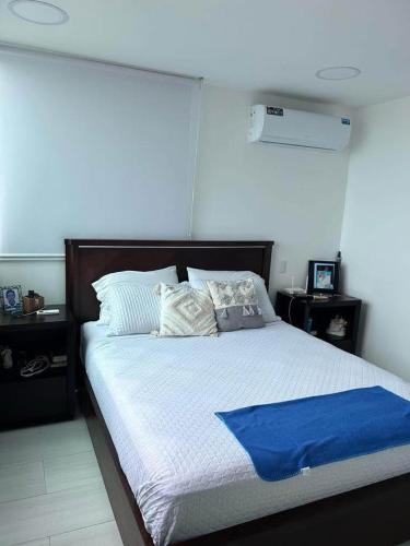 Un dormitorio con una cama con una manta azul encima. en departamento salinas, en Salinas