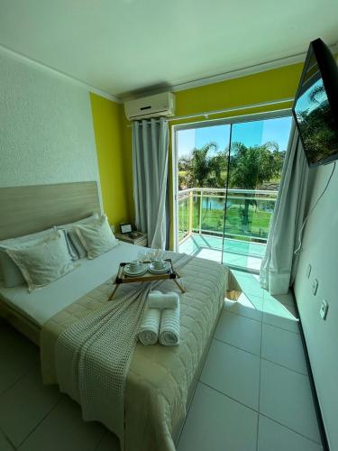 a bedroom with a bed with a table on it at Hotel Pousada Laguna Rosa in Barra de Ibiraquera