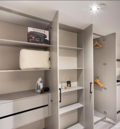 a walk in closet with white shelves and a door at Altus Hotel in Medellín