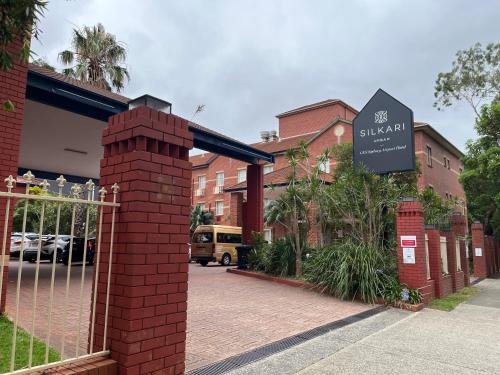 a sign in front of a building with a gate at Silkari Urban CKS Sydney Airport Hotel in Sydney