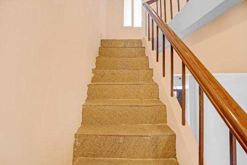a staircase with white walls and wooden railings at Hotel O Ramya Inn in Warangal