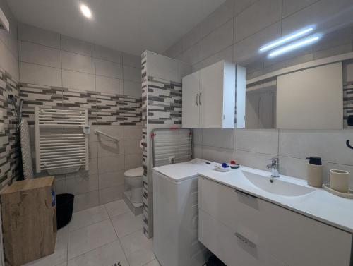 a white bathroom with a sink and a toilet at Au petit café in Châteauvillain