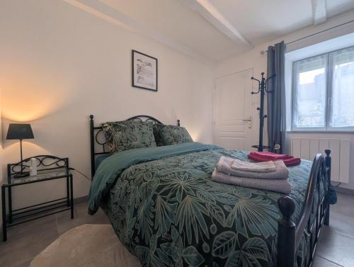 a bedroom with a bed with a green comforter at Au petit café in Châteauvillain