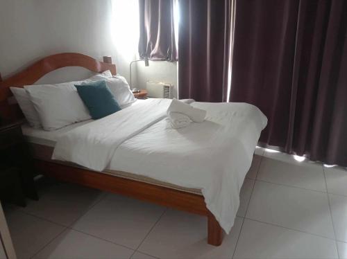 a bedroom with a bed with white sheets and blue pillows at KL Rooms at Greenbelt makati with cityview in Manila