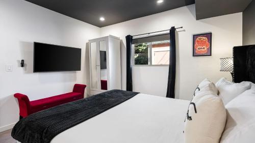 a bedroom with a white bed and a red chair at Rock n Roll by AvantStay Vibey 2BDR in Prime Hollywood Steps to Attractions in Los Angeles