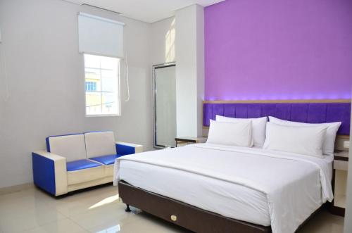 Alodia Powered by Archipelago في Tanjungkarang: غرفة نوم بسرير كبير وجدار ارجواني