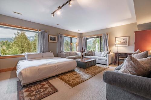 a bedroom with a large bed and a living room at Heron Chalet by Outpost Whistler in Whistler
