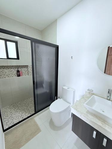 a white bathroom with a toilet and a sink at Casa Honeybun in Mérida