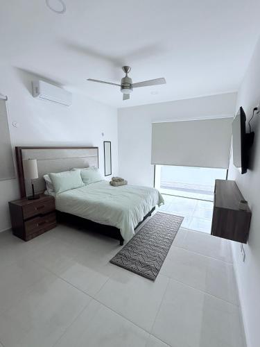 a white bedroom with a bed and a rug at Casa Honeybun in Mérida