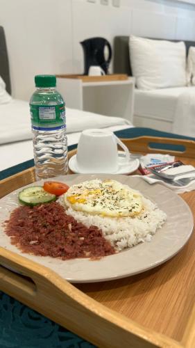 Un plato de comida con arroz y una botella de agua. en NOVADECI Suites, en Manila