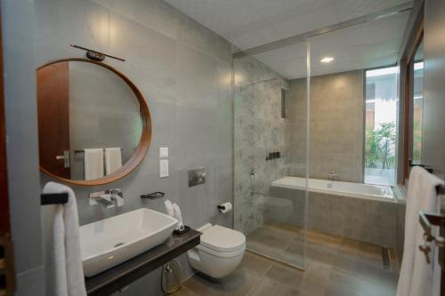 une salle de bain avec un lavabo, des toilettes et un miroir dans l'établissement Emerald Resort Hikkaduwa, à Hikkaduwa