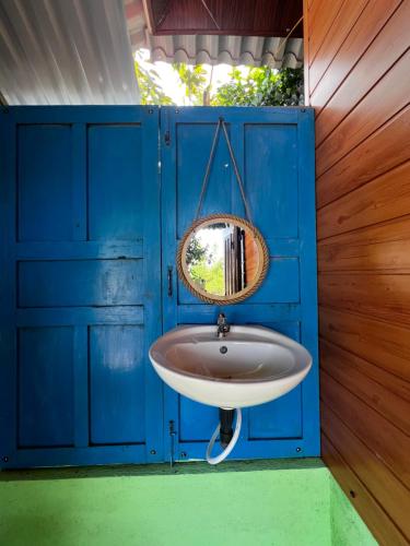 a bathroom with a blue wall with a sink at The Rustic Tree Farm in Thôn An Thạnh