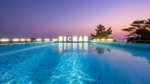 una piscina por la noche con un edificio iluminado en Sacheon Bichae Pension, en Sacheon