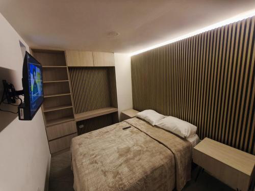 a small bedroom with a bed and a television at Barranquero Coffee Loft in Santa Rosa de Cabal