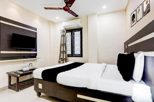 a bedroom with a bed and a flat screen tv at Super Hotel O Rajahmundry Central Railway Station Formerly Sanjeevi Residency in Godāvari