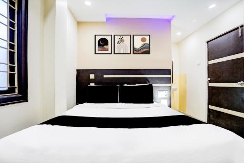a bedroom with a large white bed and pictures on the wall at Super Hotel O Rajahmundry Central Railway Station Formerly Sanjeevi Residency in Godāvari