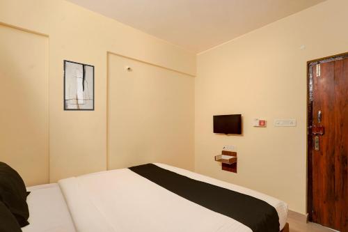 Un dormitorio con una cama y un televisor en la pared. en Hotel O Thanisandra Railway Station Formerly Urban Drift, en Yelahanka