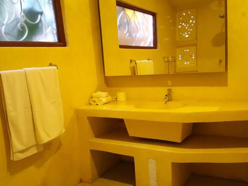 a yellow bathroom with a sink and a mirror at Juada Garden in Seminyak