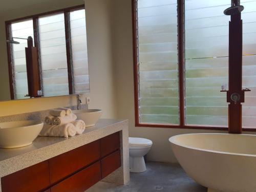 a bathroom with two sinks and a tub and a toilet at Juada Garden in Seminyak