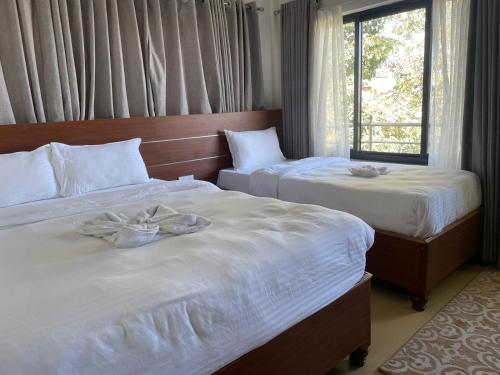 two beds in a hotel room with towels on them at Hotel Indrawoti and Resort in Dhulikhel