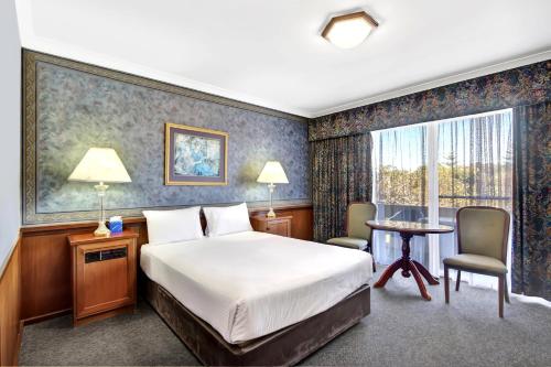 バンバリーにあるThe Clifton Motelのベッドとテーブルと窓のある寝室