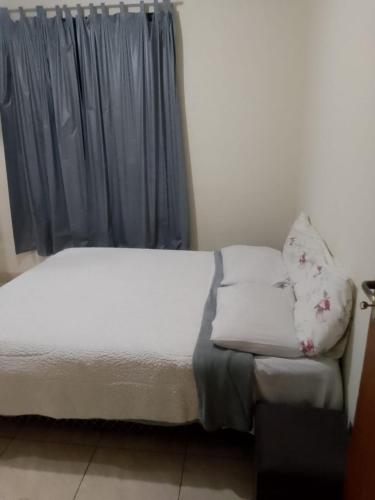 un letto con lenzuola e cuscini bianchi accanto a una finestra di Casa Petrópolis a Petrópolis