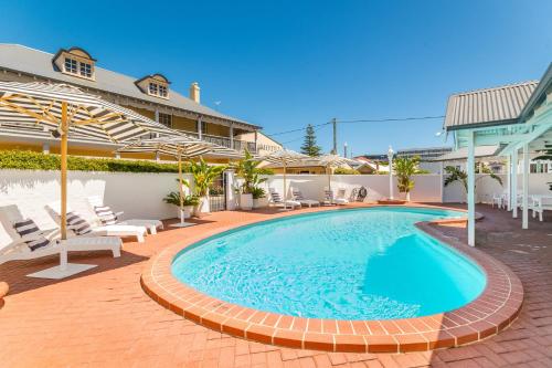 バンバリーにあるThe Clifton Motelの椅子と建物のあるプール