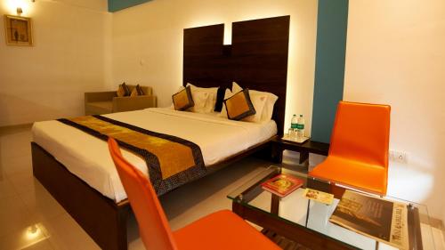 a bedroom with a bed and a desk and a chair at Hotel Golden View in Shirdi