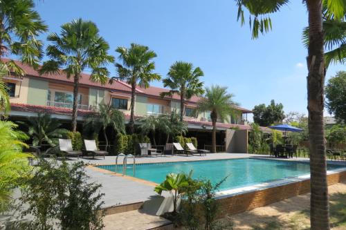 a resort with a swimming pool and palm trees at Baan Bee Residence in Nong Prue