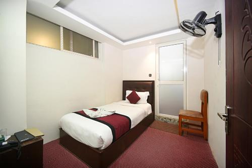 una piccola camera da letto con un letto e una finestra di Hotel De Universal a Kathmandu