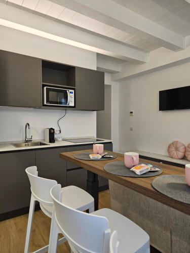 una cucina con tavolo, sedie bianche e bancone di NALI Apartment 1 a Civitanova Marche