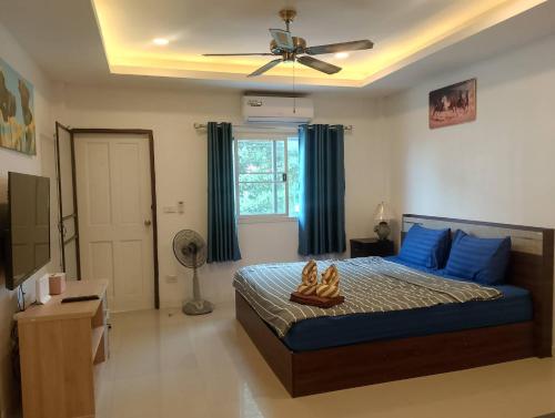 a bedroom with a bed with blue pillows and a ceiling fan at AURA House in Pattaya South