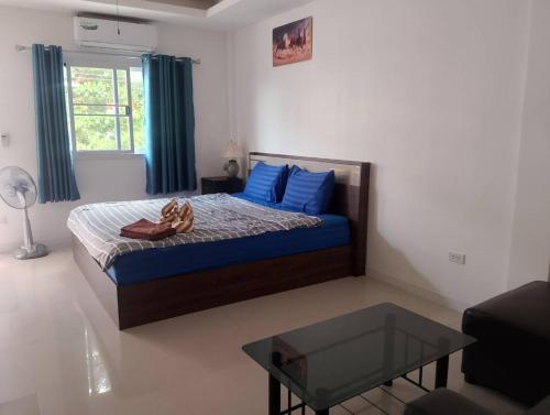 a bedroom with a bed with blue pillows and a table at AURA House in Pattaya South